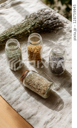 Exploring organic herbs in glass jars with dried flowers on a rustic table setting, highlighting natural alternatives for homeopathy and cosmetics 128759945
