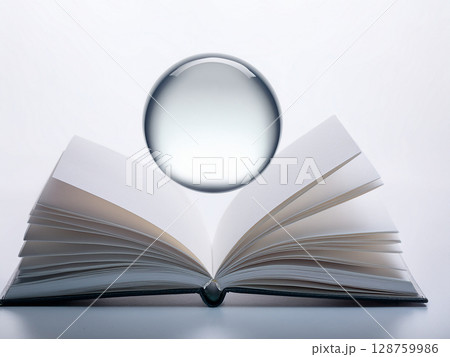 開いた本の上に白色の球が浮かんでいる 開いた本の上に白色の球が浮かんでいる 128759986