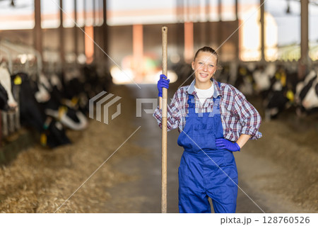 Young female farmer standing with pitchfork Young female farmer standing with pitchfork 128760526