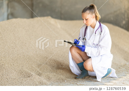 Girl vet with tablet inspect granulated feed in storage Girl vet with tablet inspect granulated feed in storage 128760539