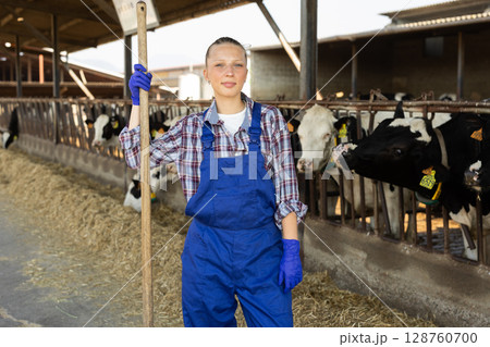 Young female farmer standing with pitchfork Young female farmer standing with pitchfork 128760700