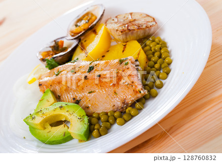 Fried trout fillets served with vegetables, seashells and avocado at plate 128760832