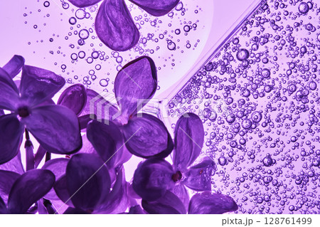 A petri dish with a beautiful serum texture on a purple background with lilac flowers. A petri dish with a beautiful serum texture on a purple background with lilac flowers. 128761499