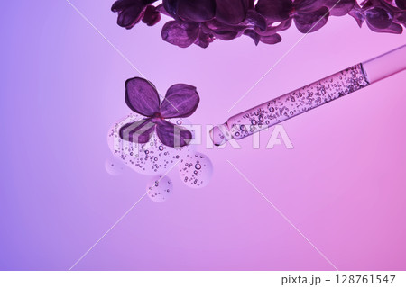 Cosmetic pipette with serum and lilac flowers on a purple background. 128761547