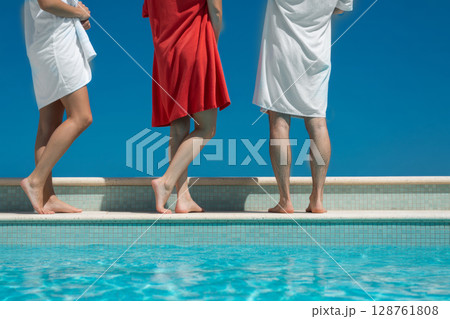 Group of individuals standing by a swimming pool, enjoying sunny day with clear blue sky Group of individuals standing by a swimming pool, enjoying sunny day with clear blue sky 128761808