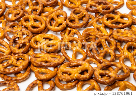 Background consisting of small traditional beer pretzels with salt isolated on white background 128761961