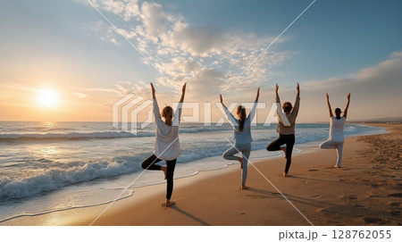 Group of women practicing yoga in tree pose on a sandy beach at sunrise with waves in the background Group of women practicing yoga in tree pose on a sandy beach at sunrise with waves in the background 128762055