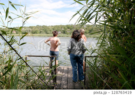 Women on the pier by the river Women on the pier by the river 128763419