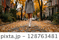 Woman in Animal Print Coat and White Boots Walking on an Autumn Street 128763481