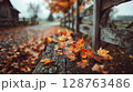 Wet Autumn Leaves on Rustic Wooden Bench 128763486