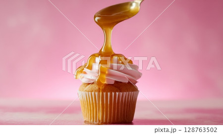 A Delicious Cupcake with Sweet Caramel Drizzle displayed beautifully on a Pink Background A Delicious Cupcake with Sweet Caramel Drizzle displayed beautifully on a Pink Background 128763502