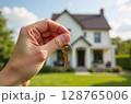 Hand holding house keys in front of a new home. Concept of buying, renting, or selling real estate, homeownership, and property investment. AI generated image 128765006