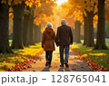 Senior couple walking hand in hand through a beautiful autumn park. Romantic retirement lifestyle, healthy aging, and love in later years concept. Image generated by AI 128765041