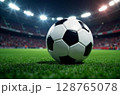 Close-up of a football soccer ball on a green field in a stadium. Football game background, sports concept, championship, match preparation. Picture generated by AI 128765078