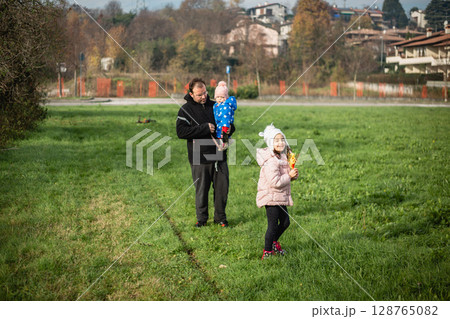 family one dad and two children walking in the field 128765082
