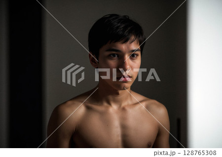 Contemplative Young Man in Dim Light 128765308