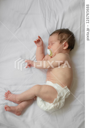 Peaceful Sleeping Newborn Baby with Pacifier on White Bed Peaceful Sleeping Newborn Baby with Pacifier on White Bed 128765688