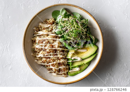 Warm Quinoa Bowl with Avocado and Tahini Drizzle on Minimal Surface 128766246