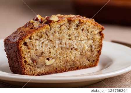 Vegan Banana Bread Slice with Nuts on White Plate, Brown Background 128766264