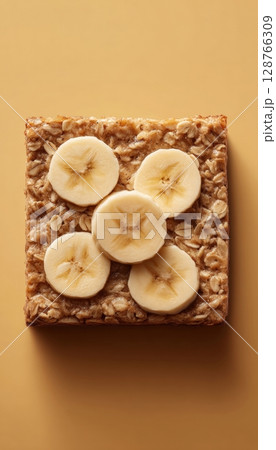 Baked Oatmeal Square with Banana Slices on Warm Background Baked Oatmeal Square with Banana Slices on Warm Background 128766309