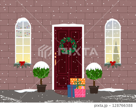 Winter Christmas cityscape. The house is decorated for the holiday. The front door with a fir wreath. Windows with garlands and snowflakes. The lights are on in the windows, preparing for the holiday 128766388