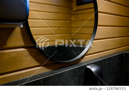 Bathroom with round mirror and wood trim 128766553
