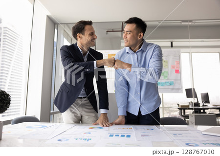 Multiethnic teammates fist bumping, making gesture of agreement, celebrate achievement Multiethnic teammates fist bumping, making gesture of agreement, celebrate achievement 128767010