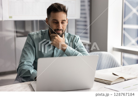 Businessman reviewing business presentation, researching information for project on laptop Businessman reviewing business presentation, researching information for project on laptop 128767184