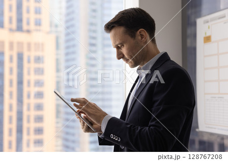 Profile of businessman dressed in formal suit using digital tablet Profile of businessman dressed in formal suit using digital tablet 128767208
