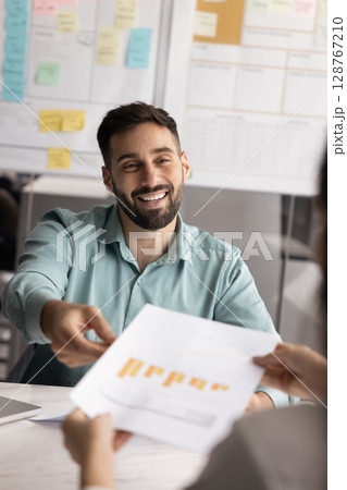 Businessman handing document with bar charts to client or colleague 128767210