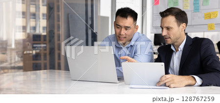 Multiracial business companions using tablet device and laptop 128767259