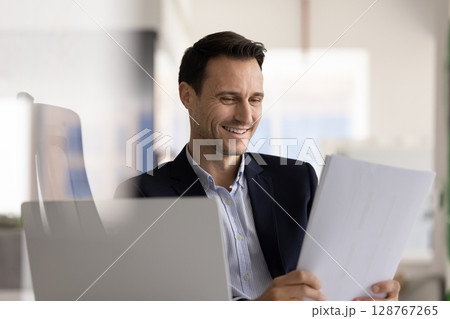Businessman reviewing financial report with good performance metrics Businessman reviewing financial report with good performance metrics 128767265