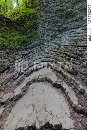 Layered rock formation on a forest slope near Partnachklamm, Garmisch-Partenkirchen, Bavaria. Unique geological structure shaped by natural erosion over thousands of years. Layered rock formation on a forest slope near Partnachklamm, Garmisch-Partenkirchen, Bavaria. Unique geological structure shaped by natural erosion over thousands of years. 128768207