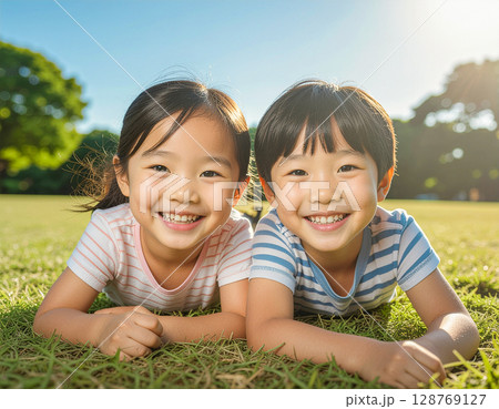 公園で芝生に寝そべる笑顔の子ども 公園で芝生に寝そべる笑顔の子ども 128769127