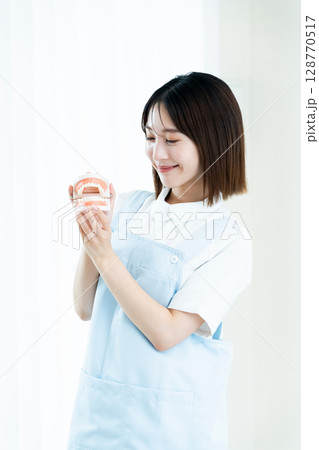 歯の模型を持つ歯科スタッフの女性 128770517