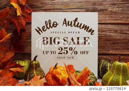 Hello Autumn Big Sale 25% text with maple leaf decoration on wooden background 128770614