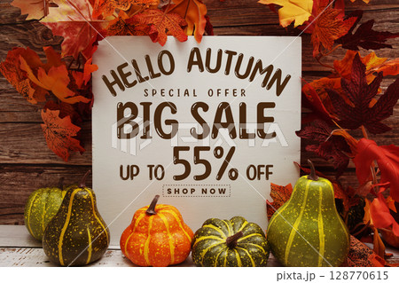 Hello Autumn Big Sale 55% text with maple leaf decoration on wooden background 128770615