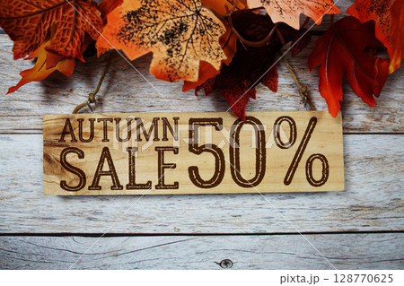 Autumn Sale 50% text with maple leaf decoration on wooden background 128770625
