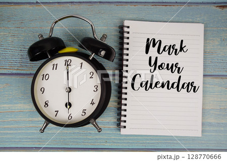 Mark Your Calendar text written on notepad with alarm clock on wooden background Mark Your Calendar text written on notepad with alarm clock on wooden background 128770666