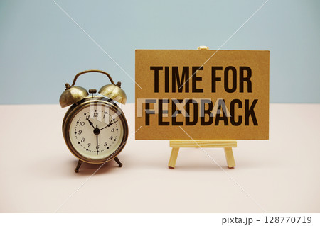 Time For Feedback text with easel and alarm clock on blue and pink background Time For Feedback text with easel and alarm clock on blue and pink background 128770719