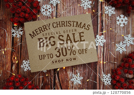 Merry Christmas Big Sale 30% text on paper card with Snowflake and LED light decoration on wooden background Merry Christmas Big Sale 30% text on paper card with Snowflake and LED light decoration on wooden background 128770856