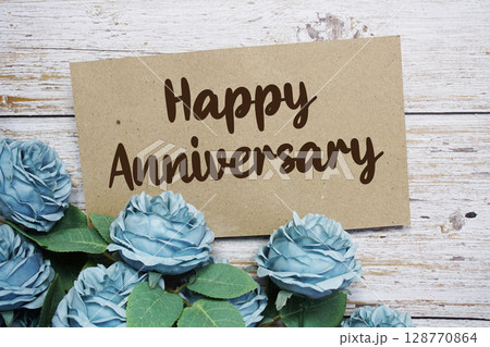 Happy Anniversary text on paper card with rose flowers bouquet on wooden background Happy Anniversary text on paper card with rose flowers bouquet on wooden background 128770864