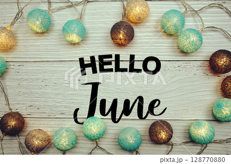 Hello June text with LED cotton balls decorated on wooden background 128770880