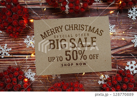 Merry Christmas Big Sale 50% text on paper card with Snowflake and LED light decoration on wooden background Merry Christmas Big Sale 50% text on paper card with Snowflake and LED light decoration on wooden background 128770889
