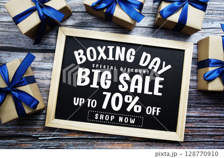 Boxing Day Big Sale 70% Off text on blackboard with present gifts on wooden background Boxing Day Big Sale 70% Off text on blackboard with present gifts on wooden background 128770910