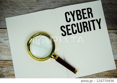 Cyber Security text message written on paper note with magnifying glass top view on wooden background 128770936