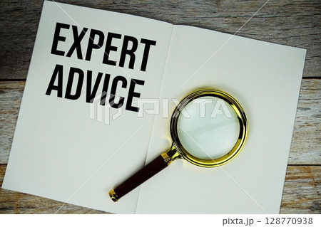 Expert Advice text message written on paper note with magnifying glass top view on wooden background 128770938