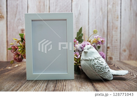 Empty frame decoration with flower bouquet on wooden background 128771043