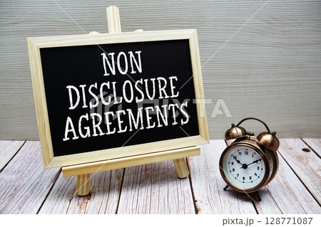 Non Disclosure Agreements text written on chalkboard with alarm clock on wooden background Non Disclosure Agreements text written on chalkboard with alarm clock on wooden background 128771087