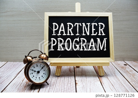 Partner Program text written on chalkboard with alarm clock on wooden background 128771126
